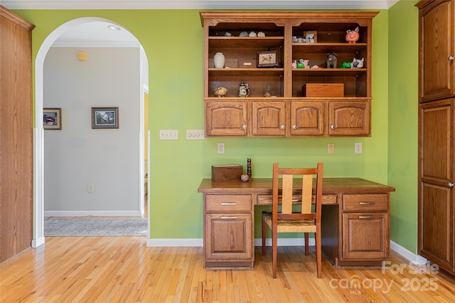 office area featuring light wood-type flooring, built in study area, crown molding, and baseboards