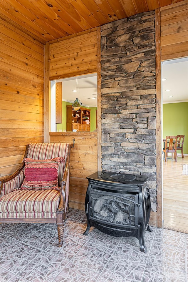 living area with wooden ceiling, a wood stove, and wooden walls