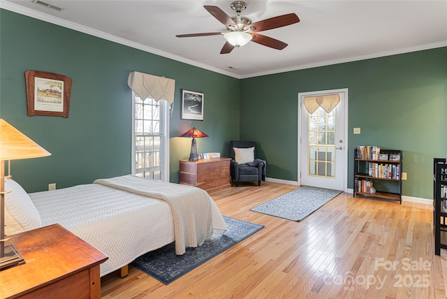 bedroom featuring ornamental molding, multiple windows, and light wood-style floors