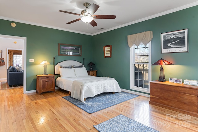 bedroom featuring light wood-style floors, baseboards, multiple windows, and ornamental molding