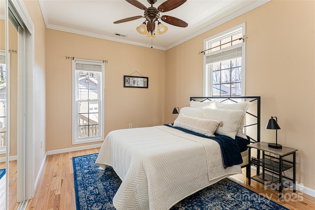 bedroom with ornamental molding, visible vents, light wood finished floors, and multiple windows