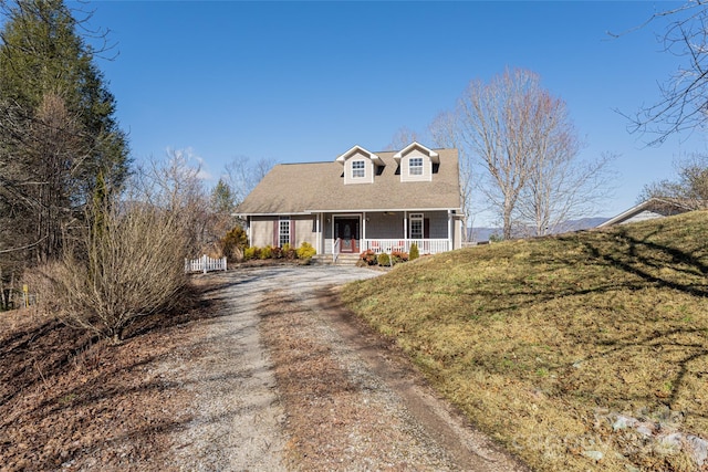 new england style home featuring dirt driveway and a porch