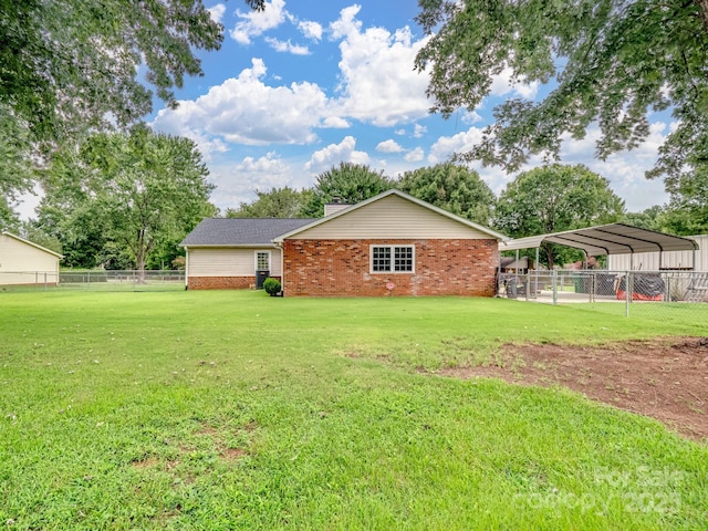 view of side of home featuring a detached carport, fence, a lawn, and brick siding