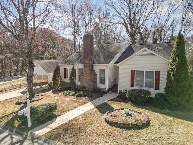 view of front facade with crawl space, a chimney, a front lawn, and roof with shingles