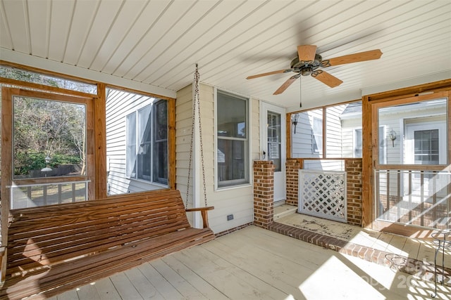 unfurnished sunroom featuring ceiling fan, a wealth of natural light, and wooden ceiling