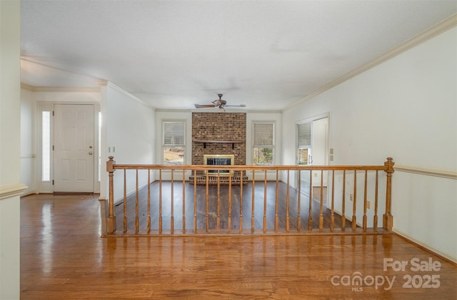 interior space featuring a fireplace, ceiling fan, crown molding, and hardwood / wood-style floors