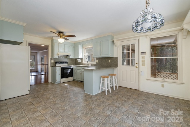 kitchen featuring white appliances, decorative light fixtures, kitchen peninsula, a breakfast bar area, and tasteful backsplash