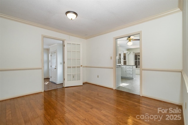 empty room with hardwood / wood-style flooring, crown molding, and a textured ceiling