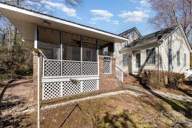 view of side of property featuring a sunroom and ceiling fan