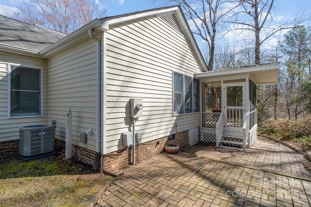 view of side of property featuring central AC, a patio area, and a sunroom