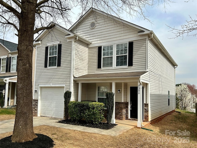 traditional home featuring stone siding, covered porch, concrete driveway, and an attached garage