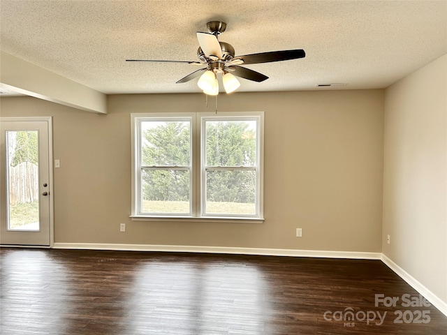 unfurnished room featuring visible vents, a ceiling fan, a textured ceiling, dark wood finished floors, and baseboards