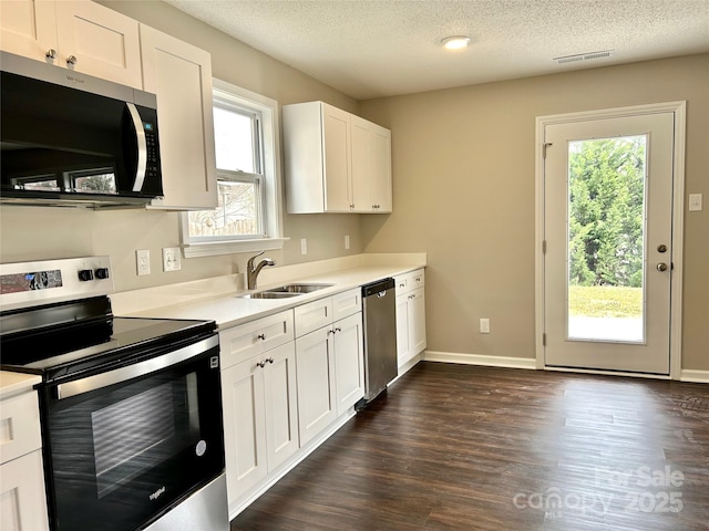 kitchen with visible vents, a sink, stainless steel appliances, light countertops, and white cabinets