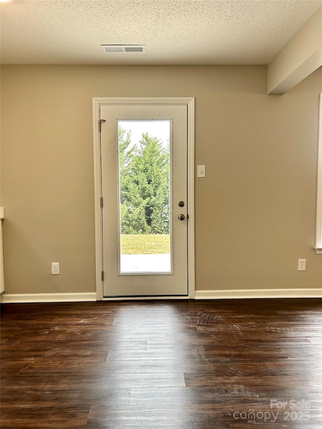 entryway featuring a textured ceiling, wood finished floors, visible vents, and baseboards