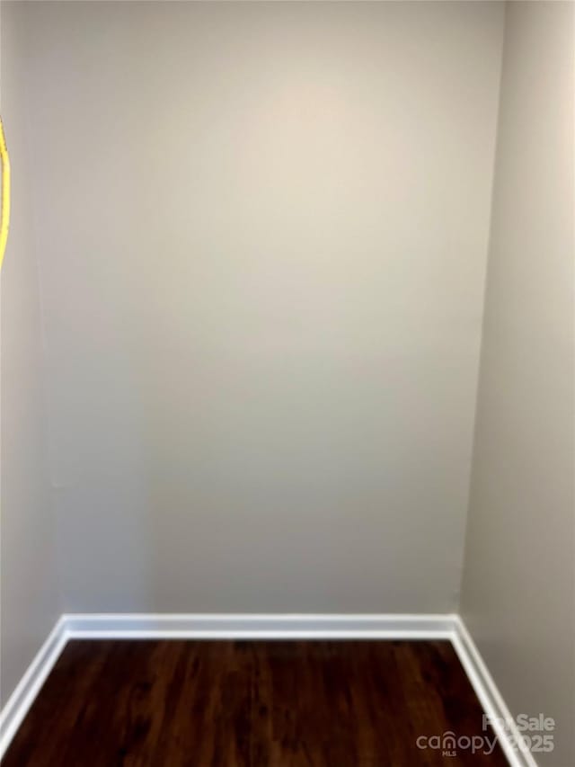 spare room with baseboards and dark wood-style flooring