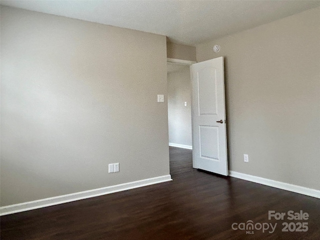 unfurnished room featuring dark wood finished floors and baseboards