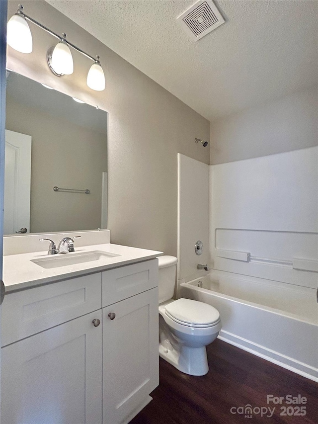 bathroom featuring vanity, wood finished floors, visible vents, a textured ceiling, and toilet