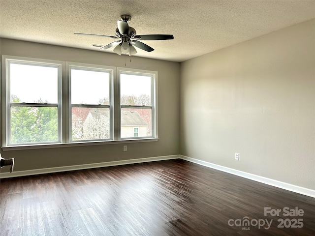 unfurnished room featuring a textured ceiling, dark wood-type flooring, baseboards, and ceiling fan