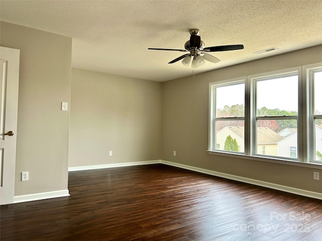 unfurnished room with a textured ceiling, baseboards, dark wood-type flooring, and a ceiling fan