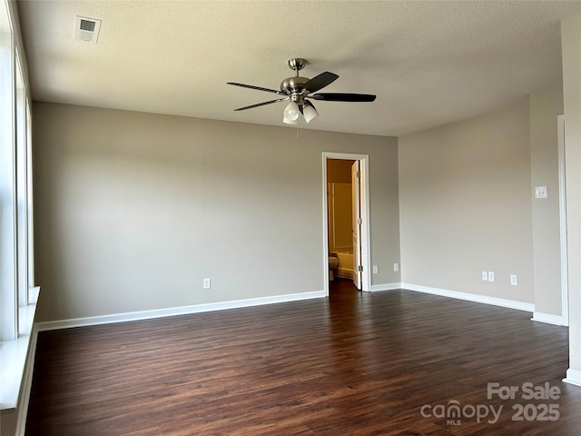 spare room featuring dark wood-style floors, baseboards, visible vents, ceiling fan, and a textured ceiling