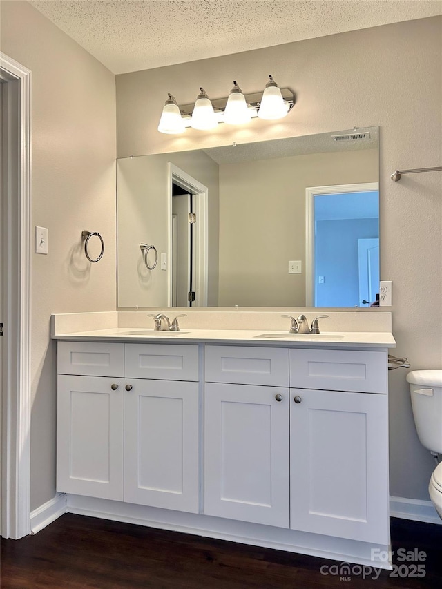 bathroom featuring a sink, visible vents, toilet, and double vanity