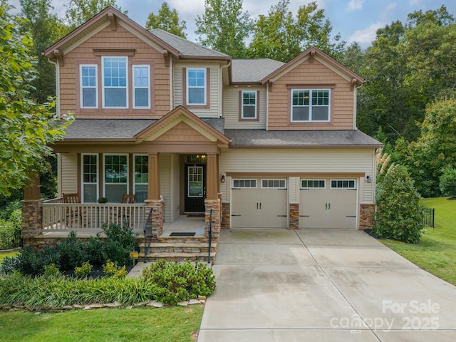 craftsman inspired home featuring a garage, covered porch, and a front lawn