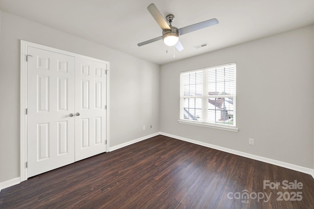 unfurnished bedroom with visible vents, a ceiling fan, dark wood-style floors, a closet, and baseboards