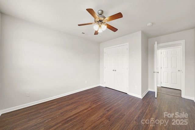 unfurnished bedroom with a ceiling fan, baseboards, visible vents, dark wood-type flooring, and a closet