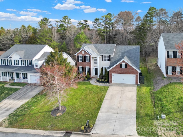 view of front of property with concrete driveway, brick siding, and a front yard