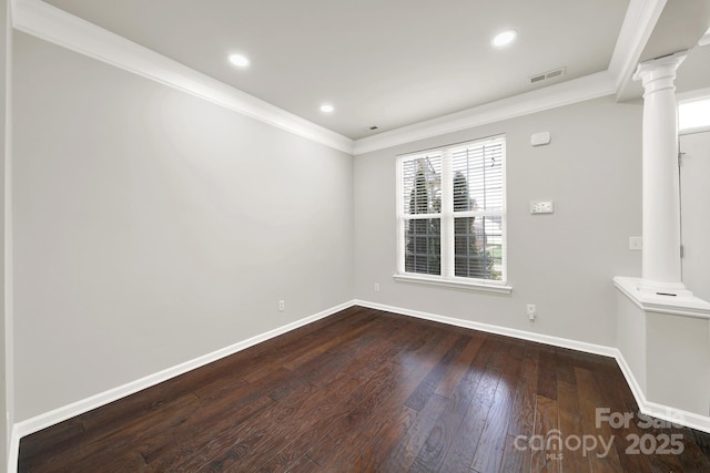 spare room featuring visible vents, crown molding, baseboards, dark wood-style floors, and ornate columns