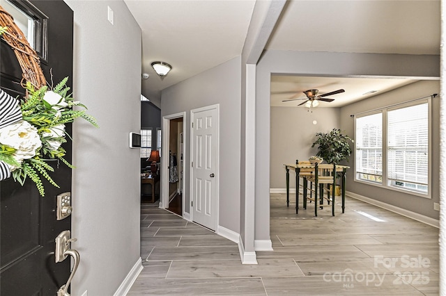 foyer with ceiling fan, wood finished floors, and baseboards