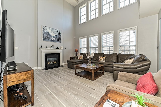 living area featuring a fireplace with flush hearth, wood tiled floor, plenty of natural light, and baseboards