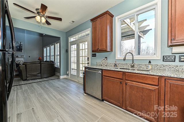 kitchen featuring light stone counters, french doors, a sink, and stainless steel dishwasher