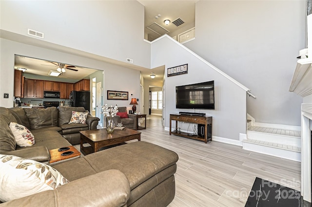 living area featuring stairs, ceiling fan, visible vents, and light wood-style floors