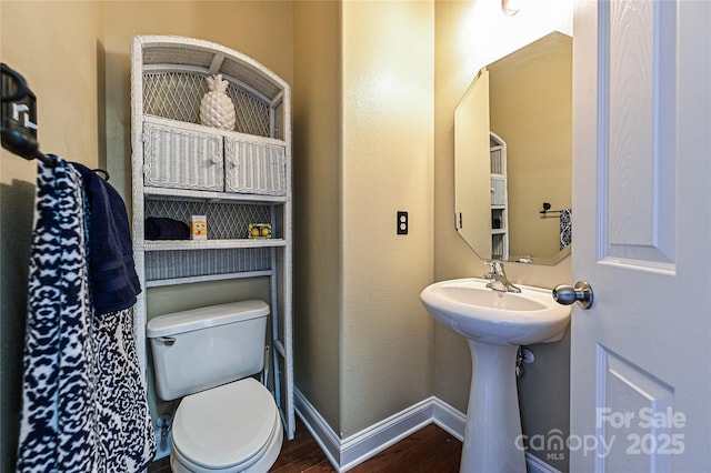 bathroom with a sink, wood finished floors, toilet, and baseboards