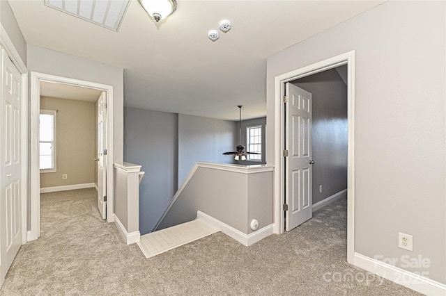 corridor with visible vents, carpet floors, an upstairs landing, and baseboards