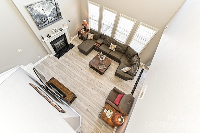 living area featuring a fireplace with flush hearth, baseboards, and wood finished floors