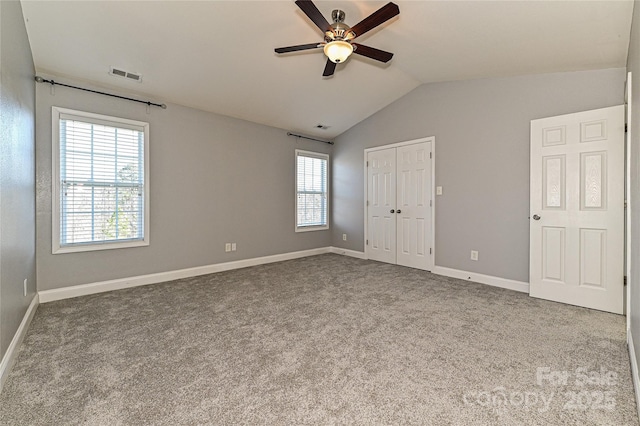 unfurnished bedroom with lofted ceiling, carpet, visible vents, and baseboards