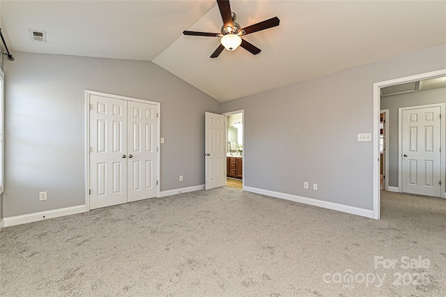 unfurnished bedroom with baseboards, visible vents, lofted ceiling, ensuite bath, and carpet flooring