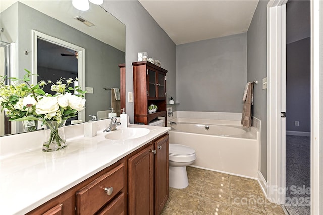 bathroom featuring toilet, visible vents, vanity, baseboards, and a bath