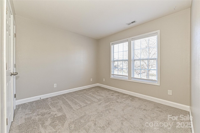 empty room featuring carpet, visible vents, and baseboards