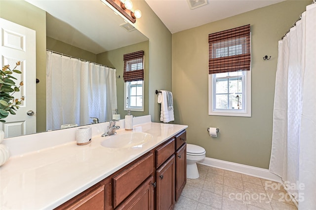 bathroom with toilet, visible vents, plenty of natural light, and baseboards