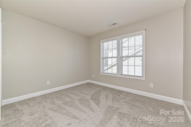 spare room with carpet floors, baseboards, and visible vents