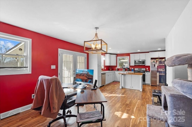 dining room with french doors, a chandelier, and light wood-type flooring