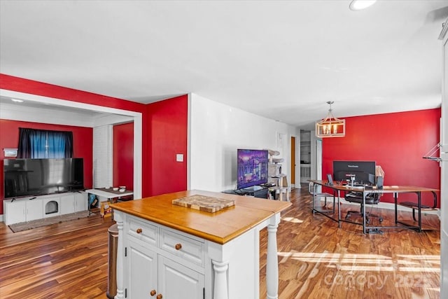 kitchen with a kitchen island, hardwood / wood-style floors, white cabinetry, butcher block counters, and hanging light fixtures