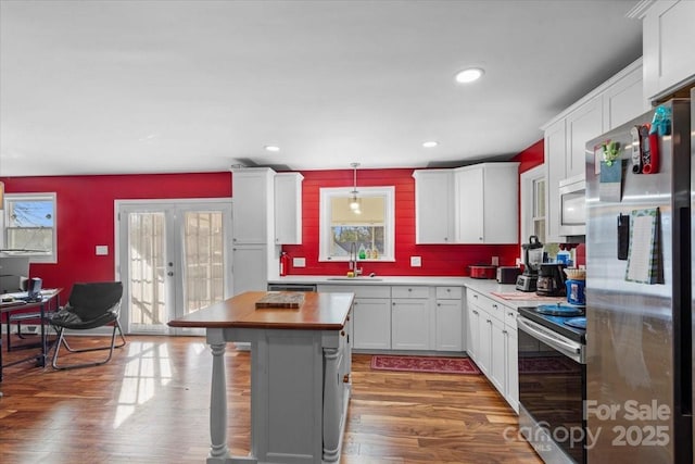 kitchen with sink, appliances with stainless steel finishes, hanging light fixtures, white cabinets, and french doors