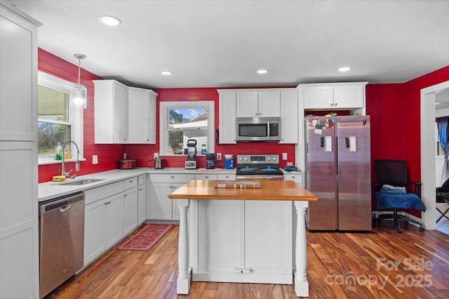 kitchen featuring white cabinetry, appliances with stainless steel finishes, sink, and hanging light fixtures