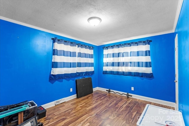 unfurnished room with wood-type flooring, ornamental molding, and a textured ceiling