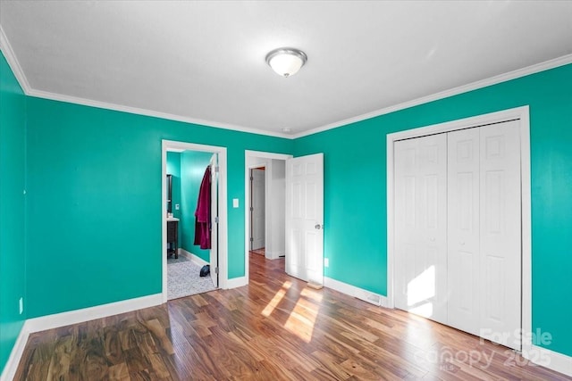 unfurnished bedroom featuring crown molding, hardwood / wood-style floors, and a closet