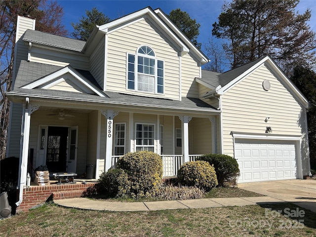traditional-style house with a chimney, a garage, a ceiling fan, driveway, and covered porch